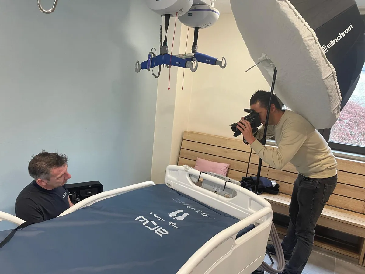 Alexis Delespierre en prise de vue sous une boîte à lumière, face à un technicien réglant un lit médicalisé