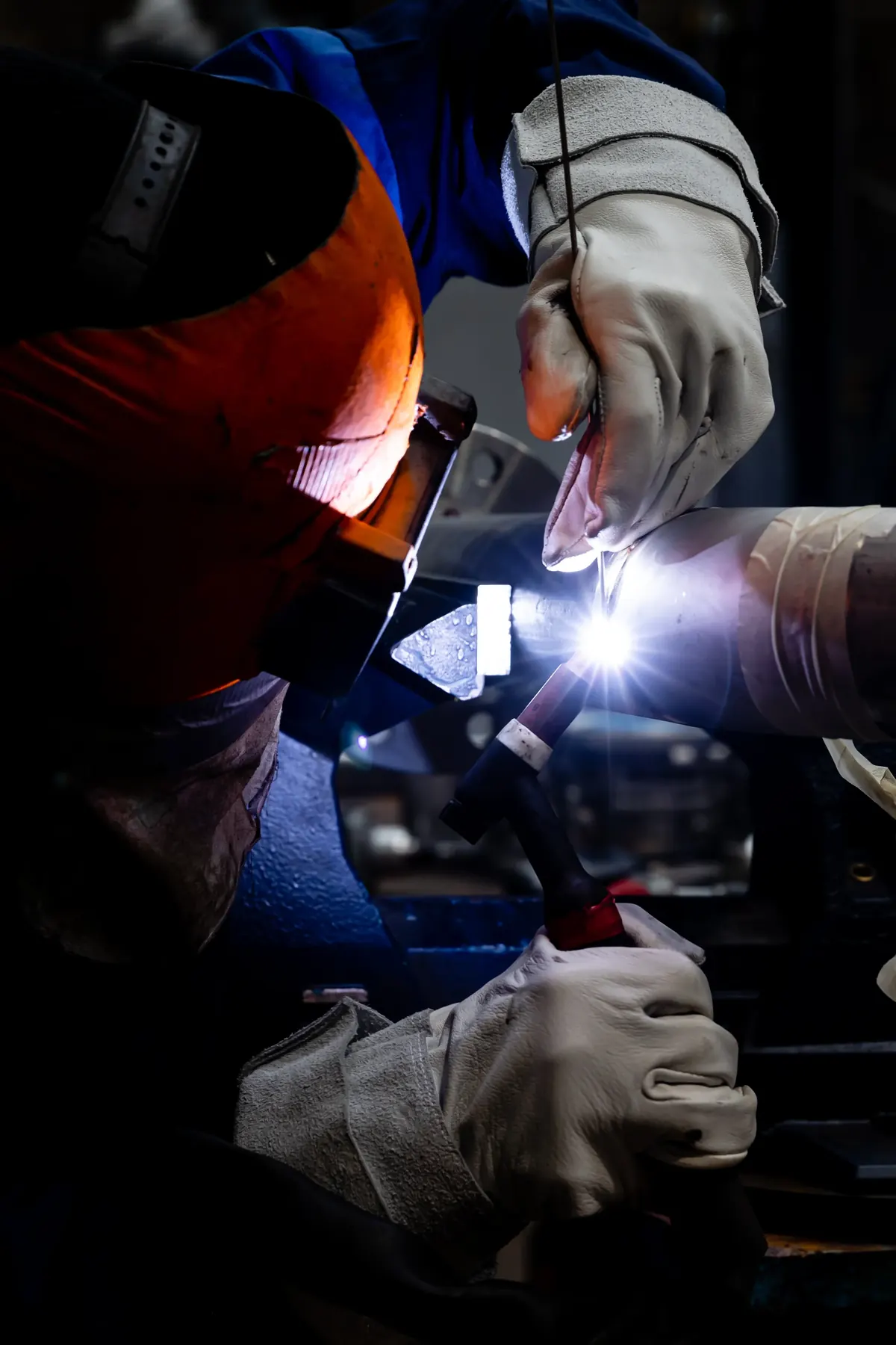 Soudeur en gants de protection, arc de soudure dans la pénombre de l’atelier