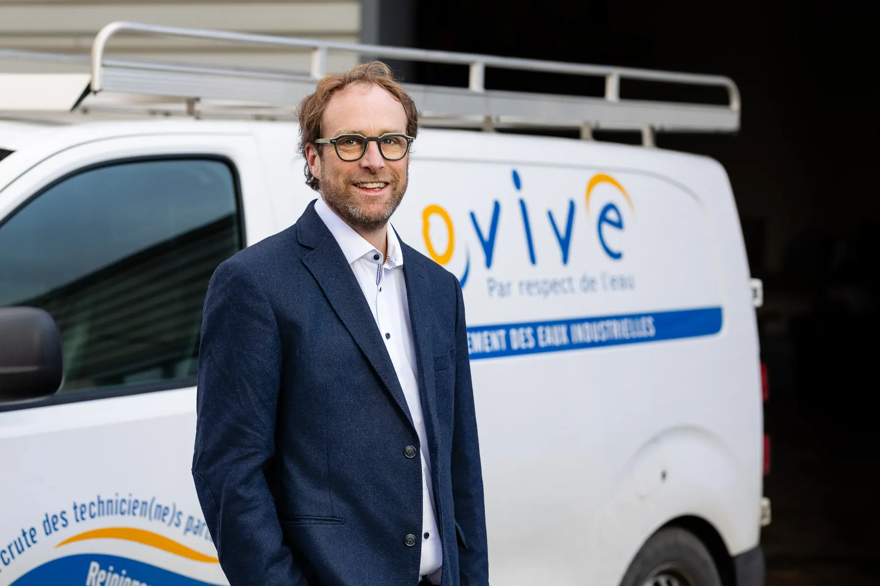 Dirigeant en costume devant un véhicule utilitaire de l’entreprise