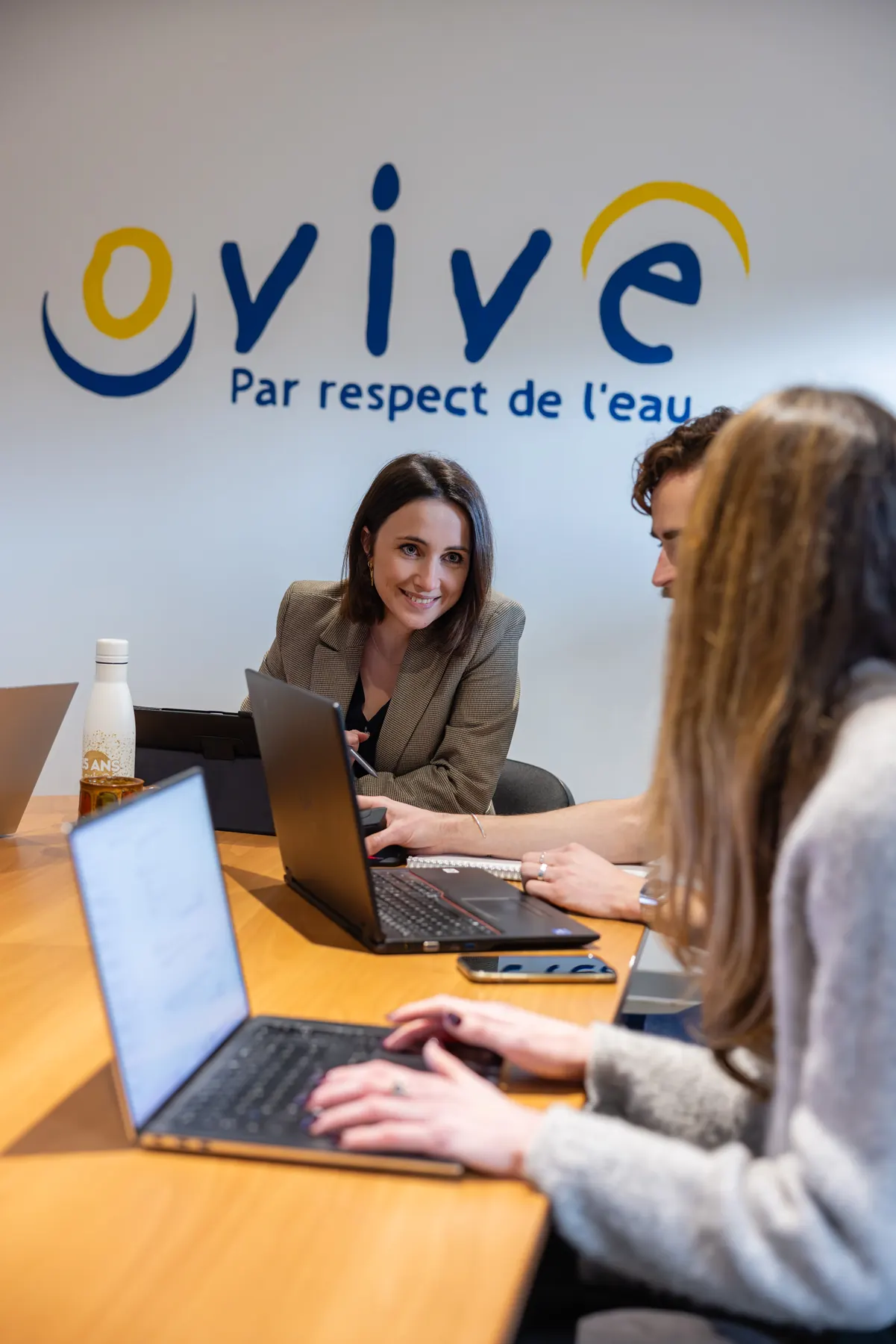 Deux collaboratrices travaillant sur ordinateur devant un mur aux couleurs de l’entreprise