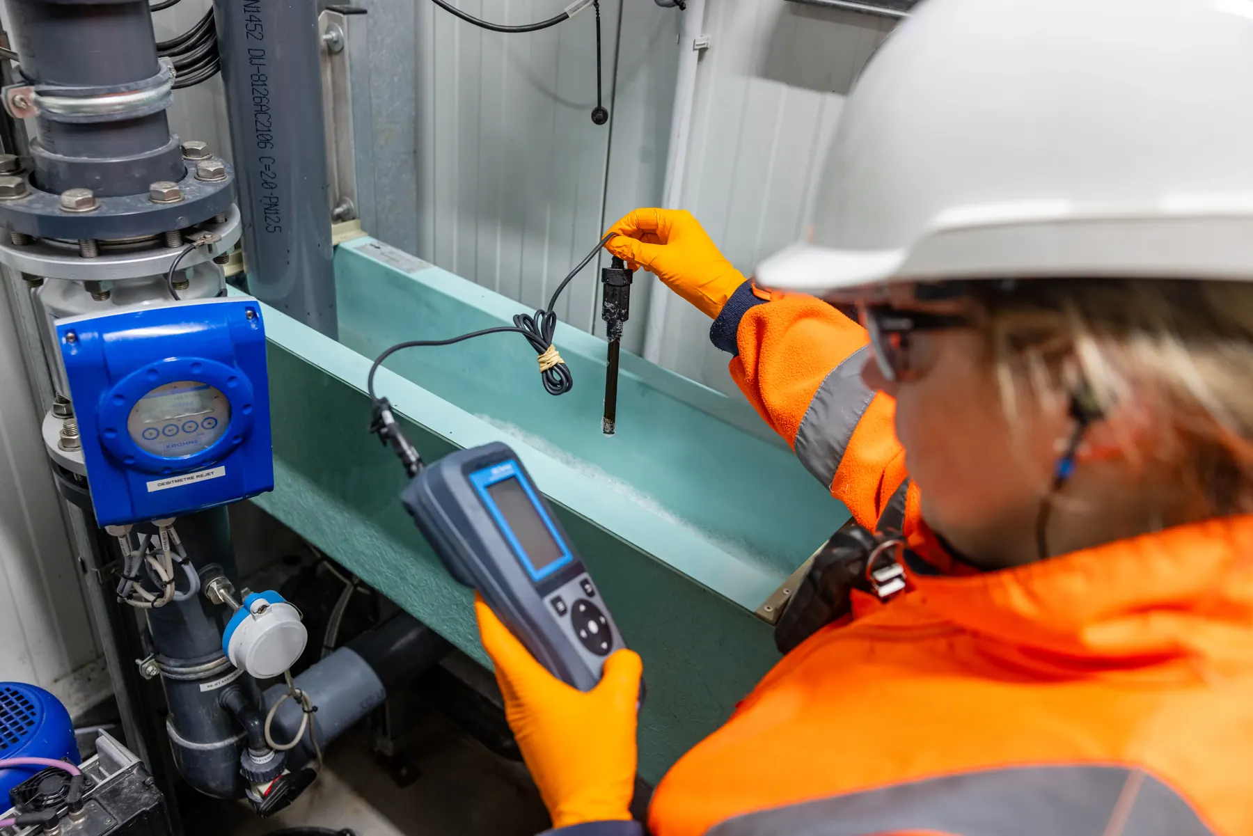 Technicienne en gants effectuant une mesure avec un appareil portable